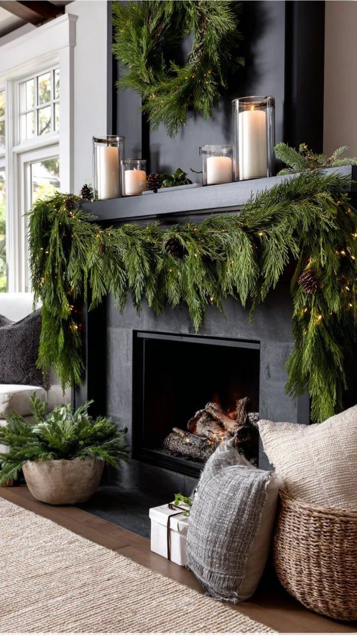 A decorated fireplace mantel with garland and lit candles for the holidays